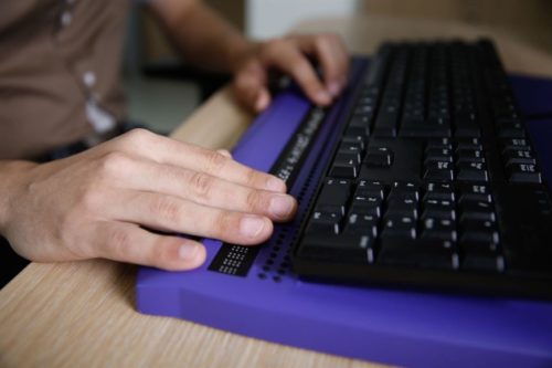 Close up of a pair of hands using a braille machine 