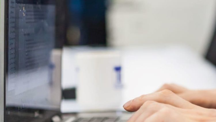 Photo of man typing on a laptop computer.