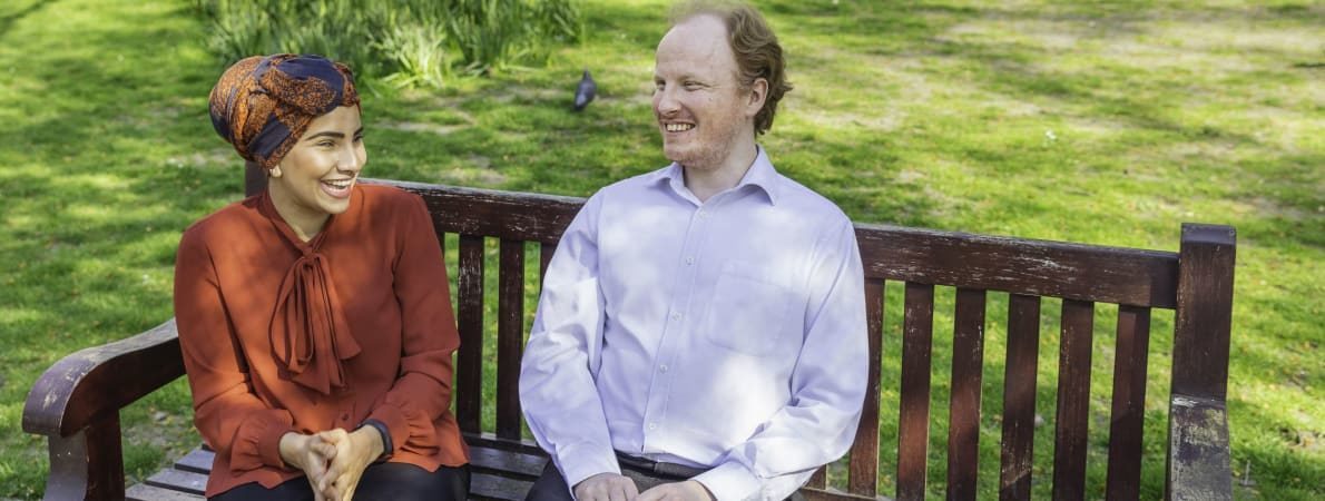 Photo of man and woman chatting on bench.