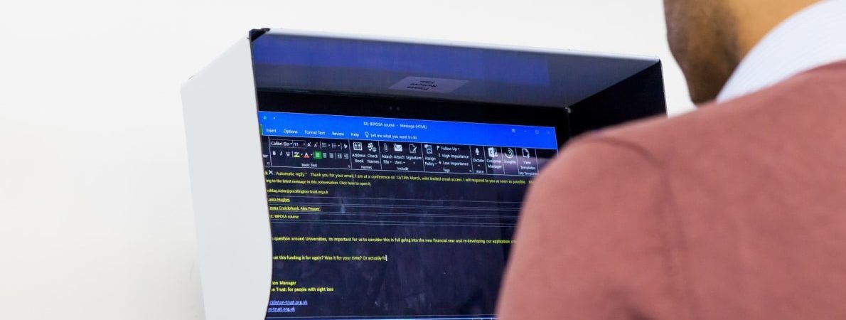 Looking over shoulder of man on computer with reversed colours on screen