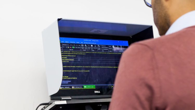 Looking over shoulder of man on computer with reversed colours on screen