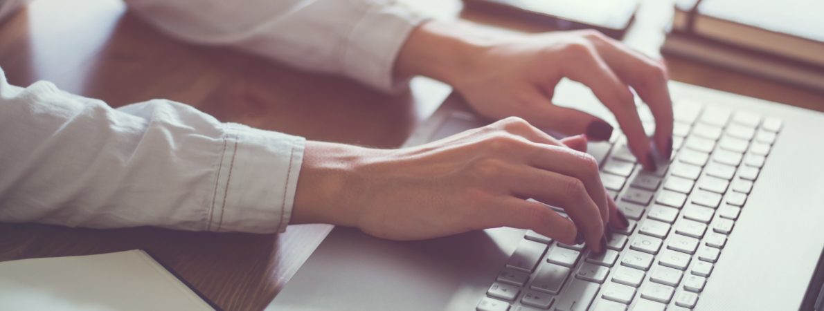 Close up of womans hands typing on a laptop