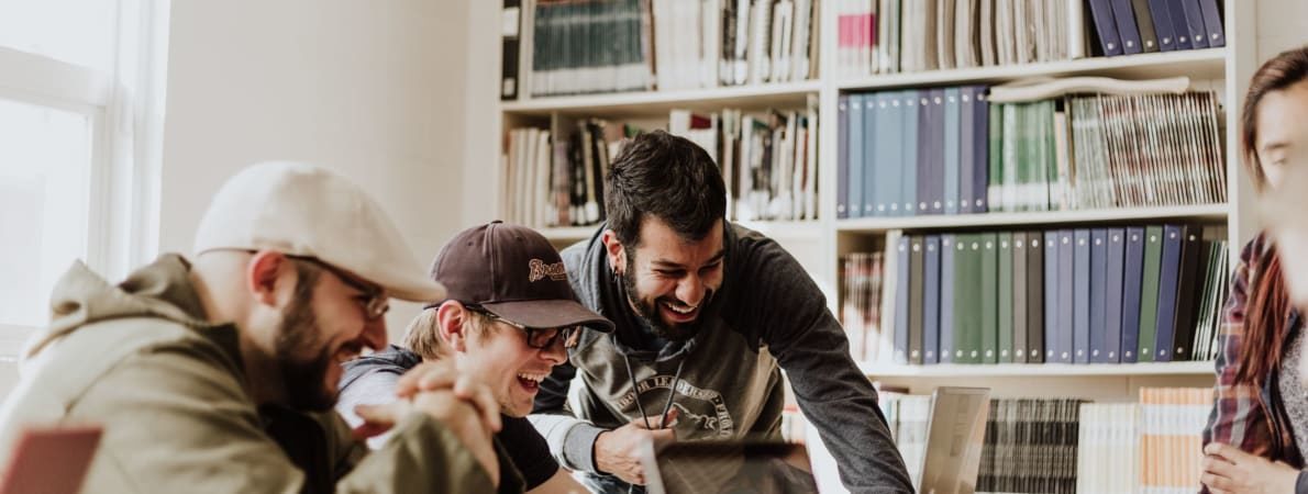 A group of students working on laptops and laughing all together