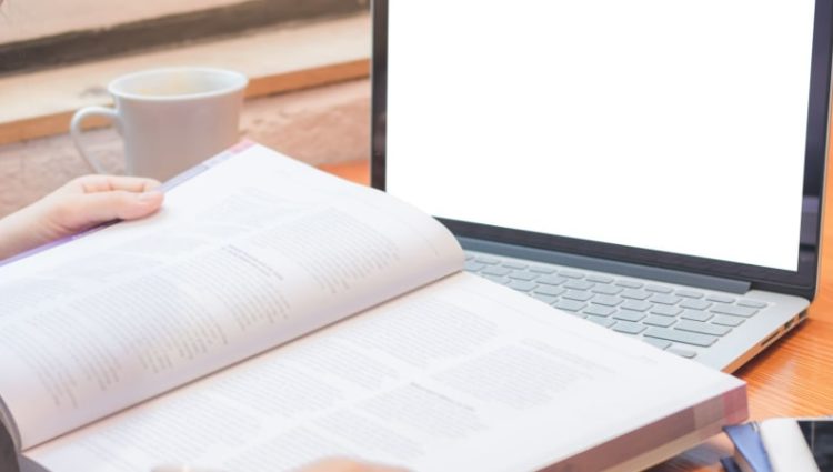 Woman studying with laptop and book