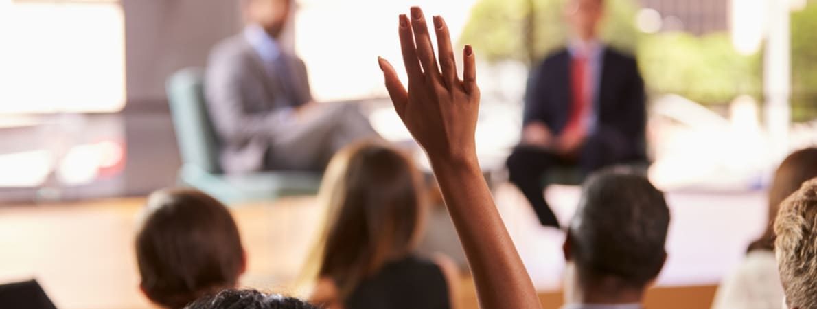 Person with hand up at a meeting