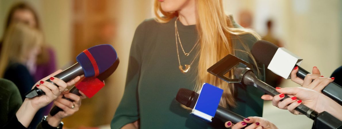 A group of people holding microphones to a women