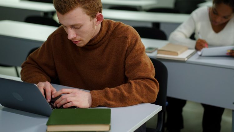 student working on laptop in an exam setting