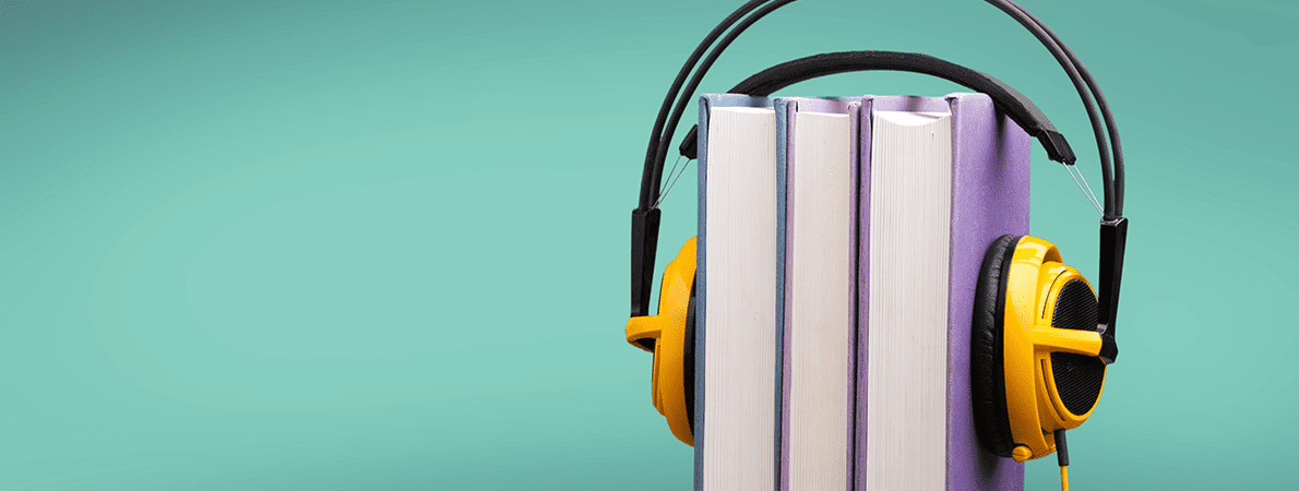 Yellow headphones over two books on a green background