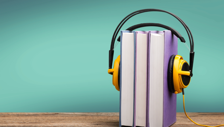 Yellow headphones over two books on a green background