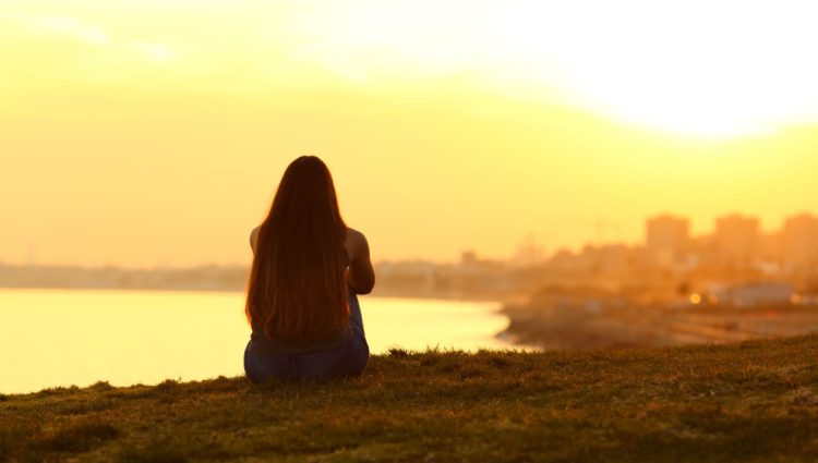 Girl look across a bay at sunset