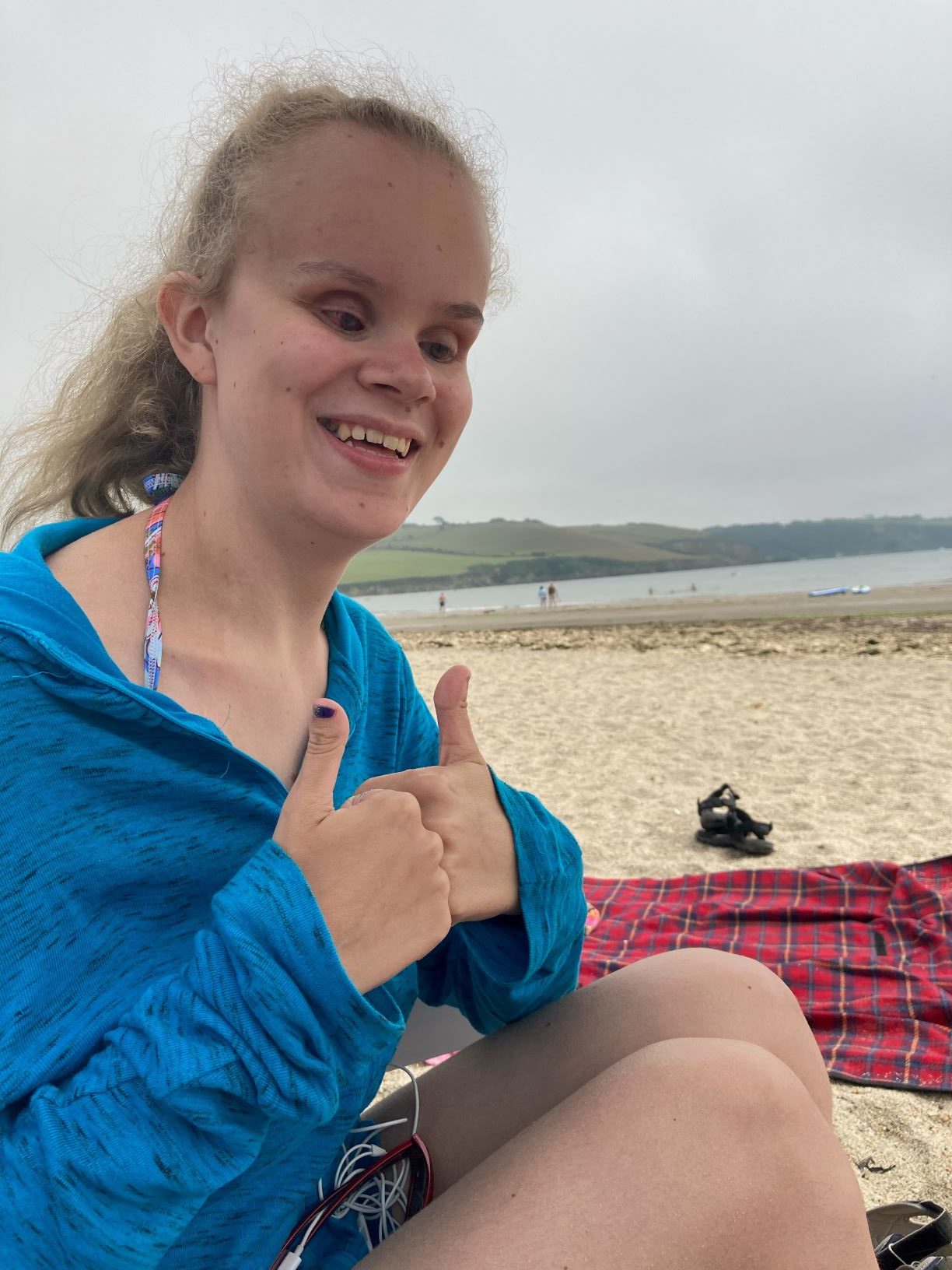 Martha Page smiling on a beach with a thumbs up