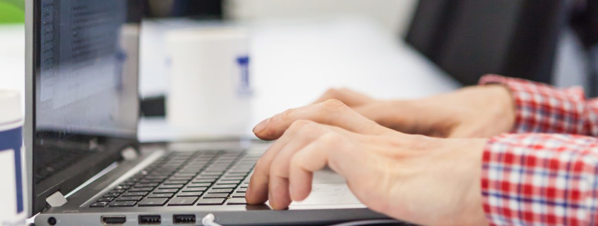 Hands typing on a laptop