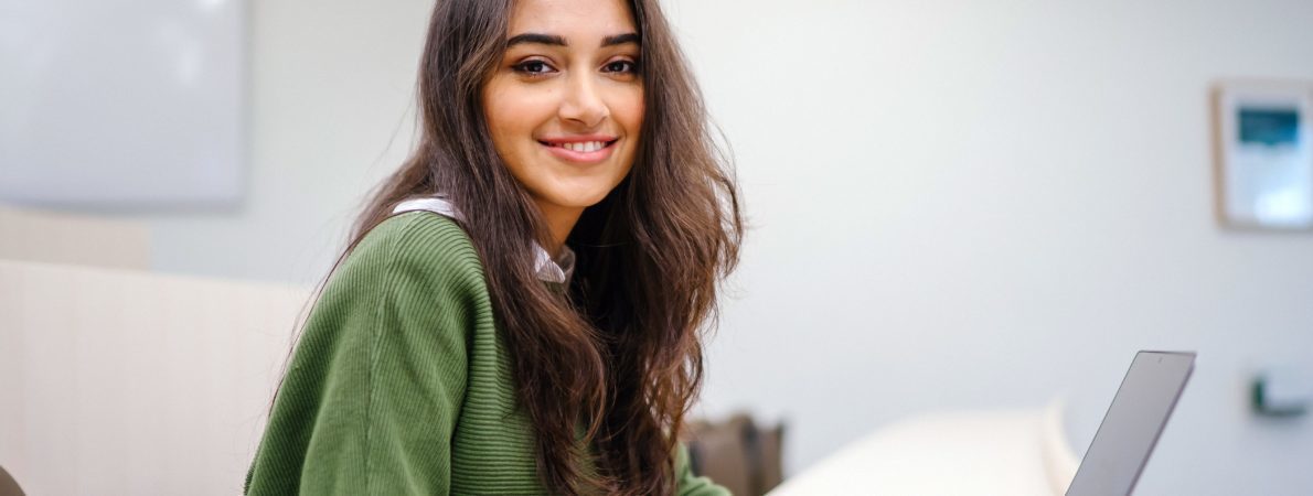 Woman smiling at the camera. She is wearing a green jumper.