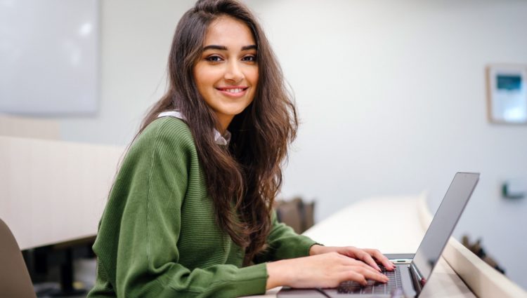 Woman smiling at the camera. She is wearing a green jumper.