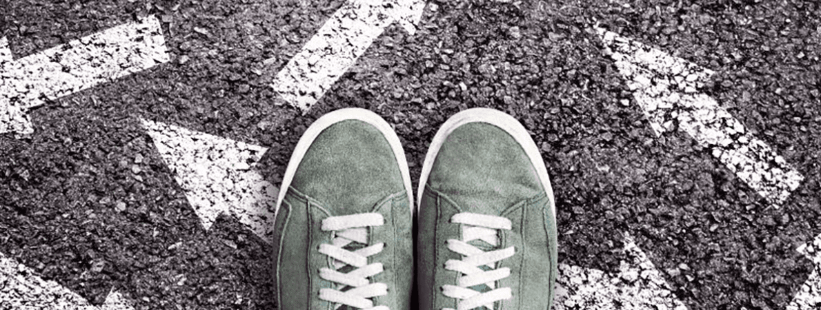 Pair of green trainers standing on white arrows on the road