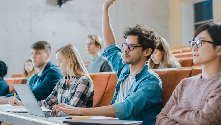 Young man with hand up in a university lecture theatre