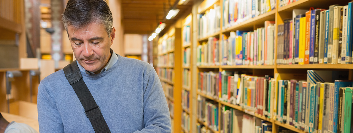 older male looking a an ipad in a university library