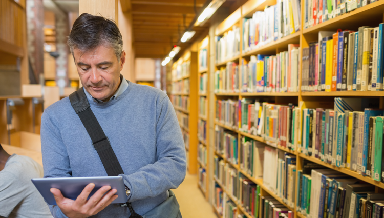 older male looking a an ipad in a university library