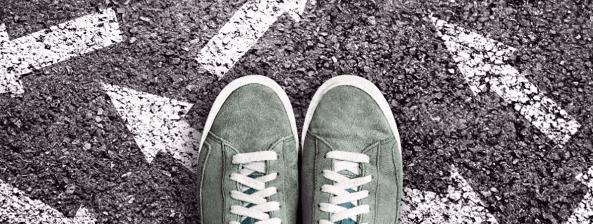 Pair of green trainers standing on white arrows on the road