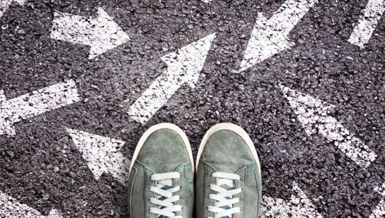 Pair of green trainers standing on white arrows on the road