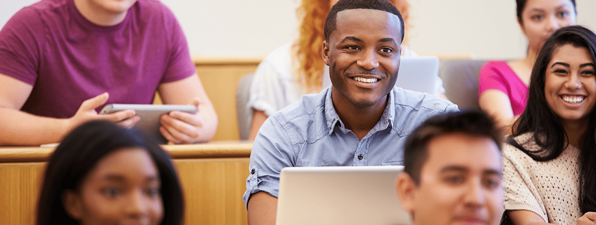 Students in a lecture theatre smiling using laptops