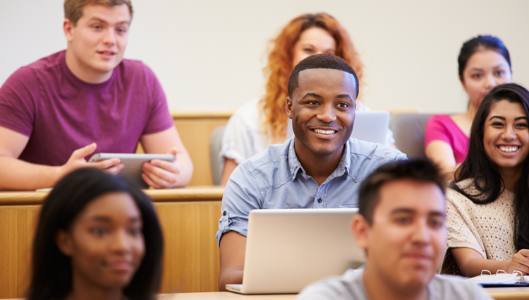 Students in a lecture theatre smiling using laptops