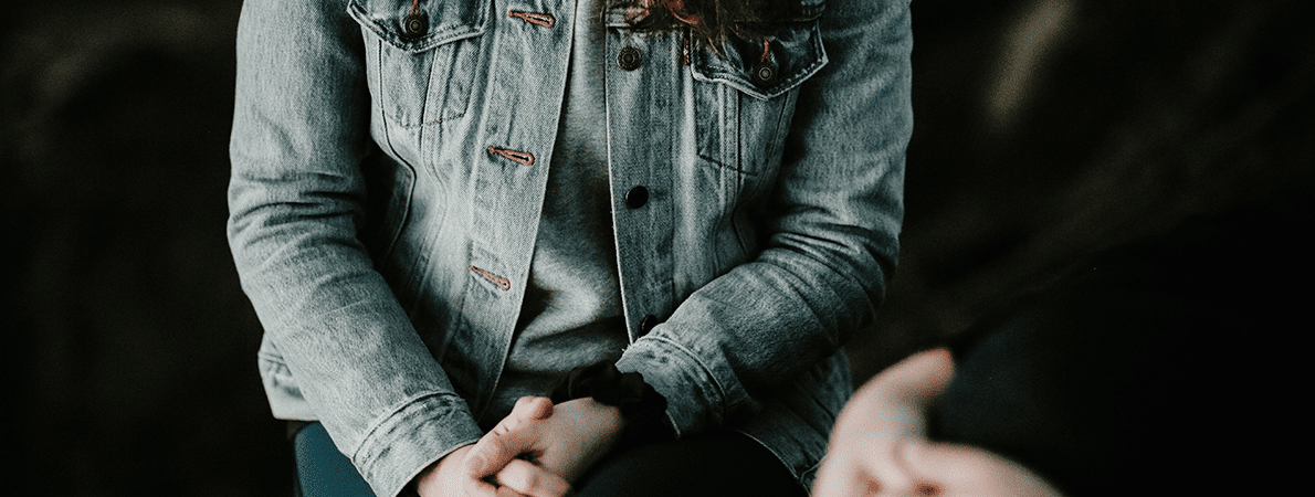 Close up of two women's hands and bodies sitting opposite each other