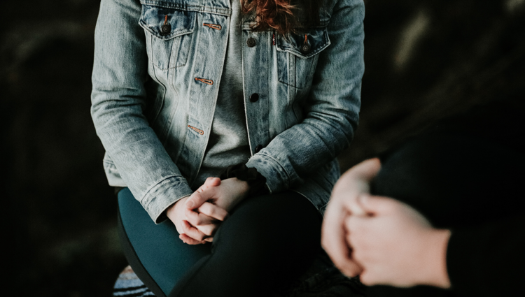 Close up of two women's hands and bodies sitting opposite each other