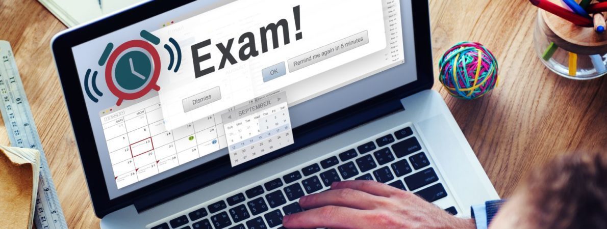 Laptop with Exam on screen with man's head, hand and a cup of coffee