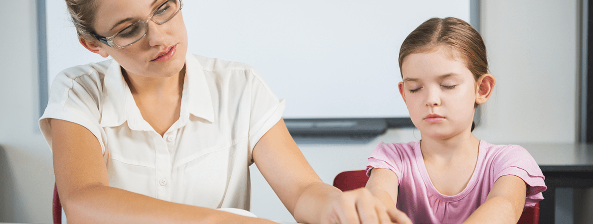 Teacher assisting blind student in library at school