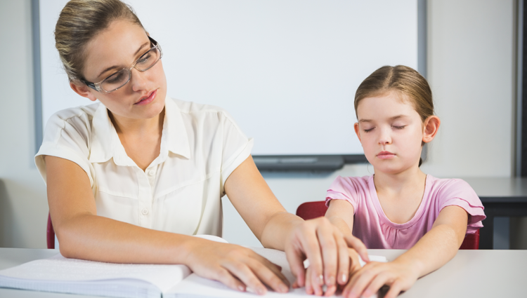 Teacher assisting blind student in library at school