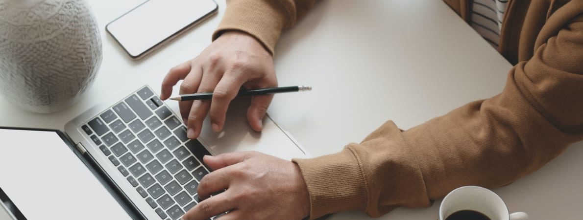 Hands at a keyboard with coffee cup and phone