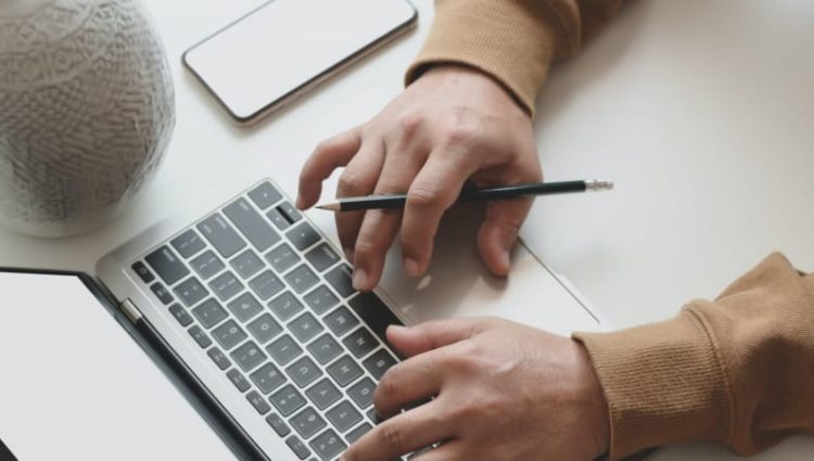 Hands at a keyboard with coffee cup and phone