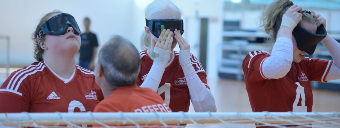 Three Goalball players putting on masks