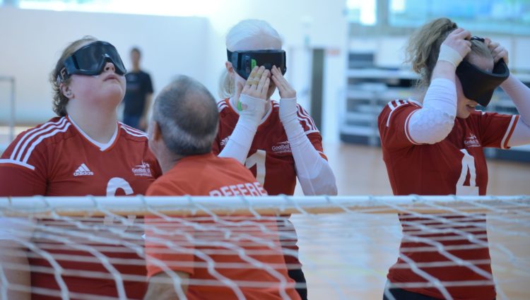 Three Goalball players putting on masks