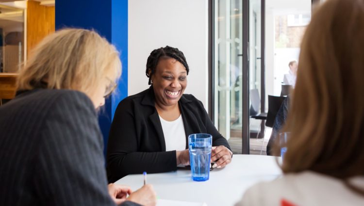 Female job candidate smiling as two Interviewers take notes