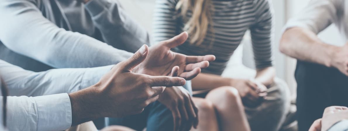 Close up photo of a man's hands speaking to a group of people