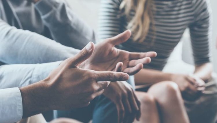 Close up photo of a man's hands speaking to a group of people