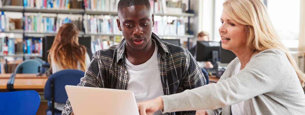 A woman showing a man something on a laptop's screen in a library