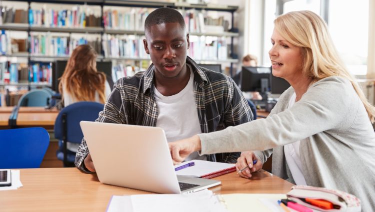 A woman showing a man something on a laptop's screen in a library