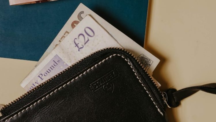 Two twenty pound notes coming out of a wallet lying on a table