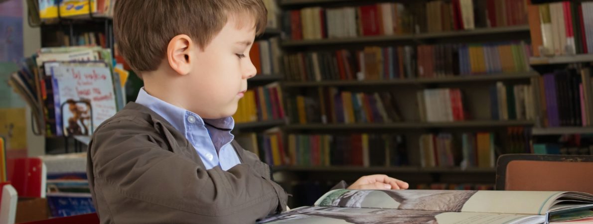 A young child reading a book in a library