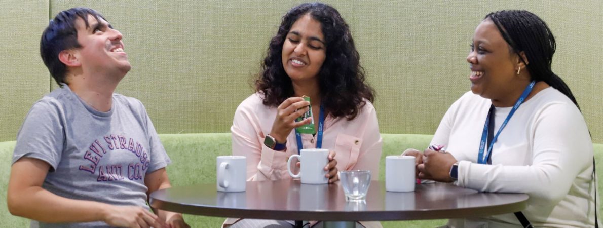 Three people chatting and laughing around a table