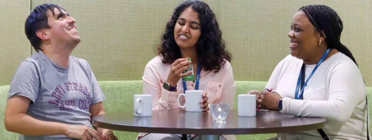 Three people chatting and laughing around a table