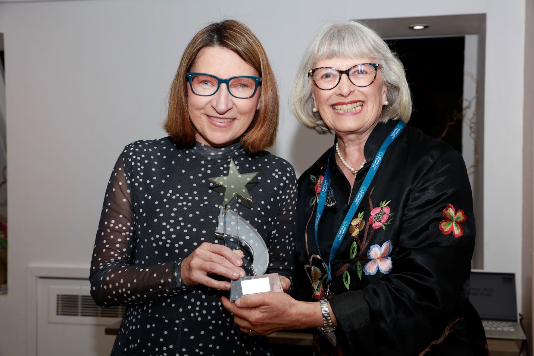 Julie Lee receiving her award by SLC member, both looking at the camera and smiling