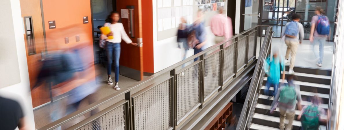 Busy college corridor with students going up stairs