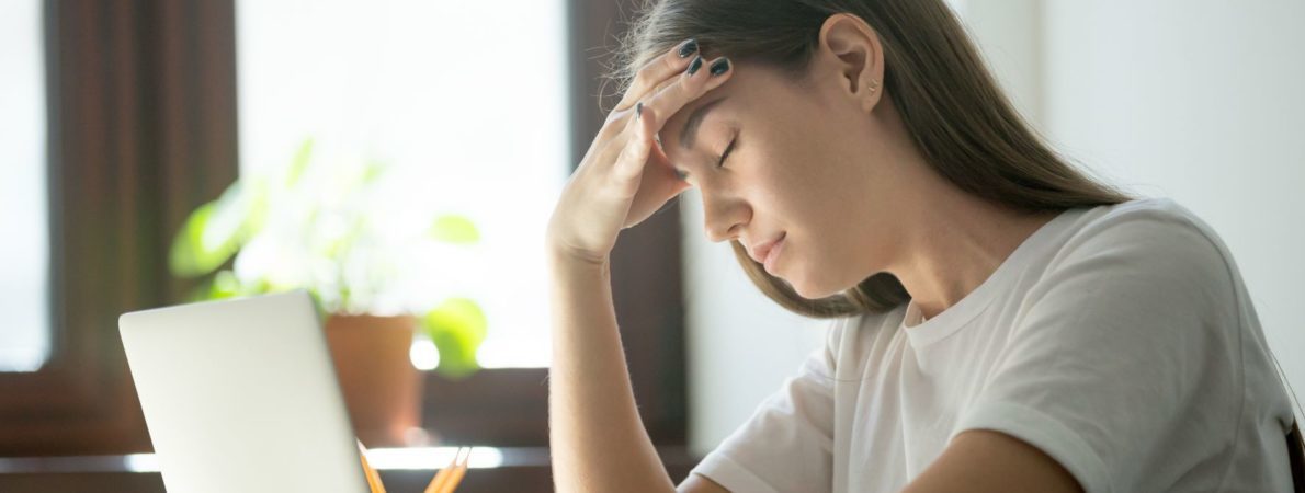 A picture of a young woman despairing in front of a laptop