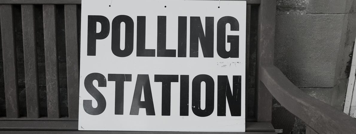 A sign reading 'Polling Booth' sits on a bench