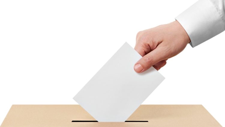 A ballot paper is being dropped into a ballot box
