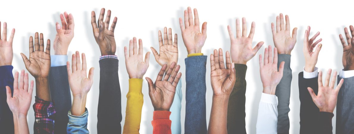 Several hands raised up in front of a white background